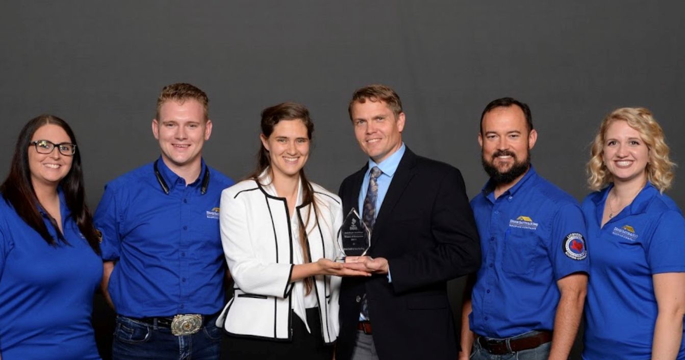 Sam and his sales team in matching polos accepting an award