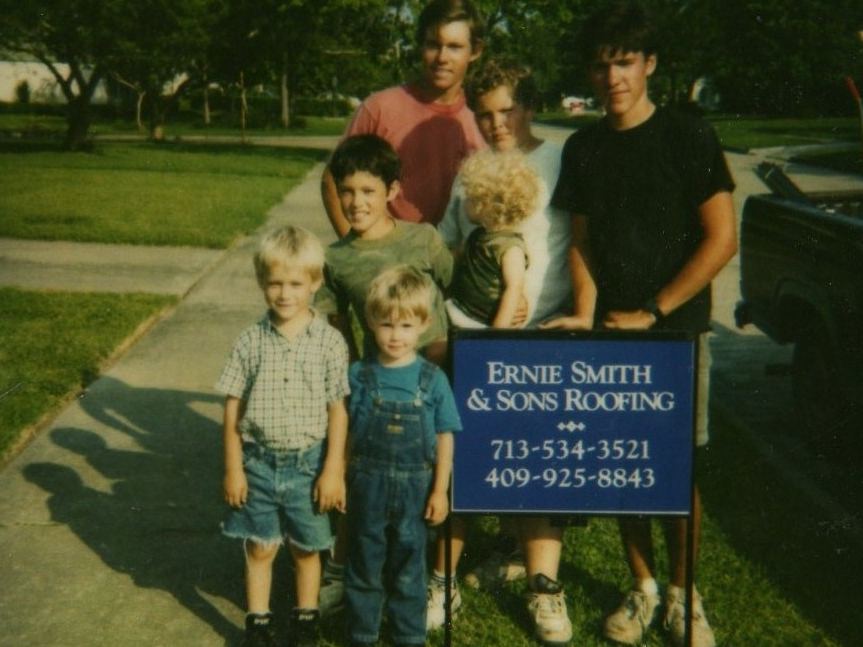 Vintage photo of young kids standing beside an Ernie Smith & Sons Roofing yard sign
