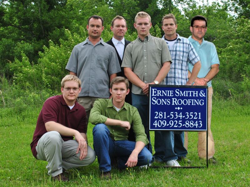 Sam with the Ernie Smith & Sons Roofing crew, kneeling beside the company yard sign