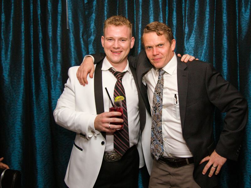 Sam in a white dinner jacket celebrating with a colleague at a company event